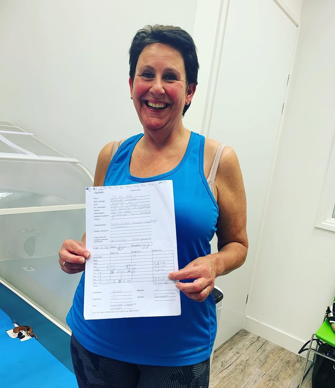 Klant met haar meetformulier na tien trainingen in de cabine